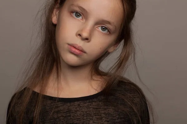 Retrato de una niña de ocho años con un estado de ánimo tranquilo, en una blusa negra y con el pelo recogido —  Fotos de Stock