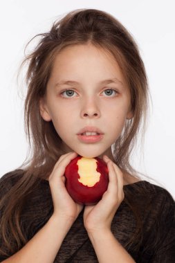 Bir elma ile güzel duygusal sekiz yaşındaki kız. Stüdyoda Fotoğraf oturumu. Kız bir siyah bluz giyiyor