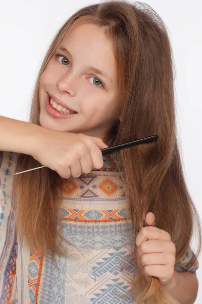 Портрет восьмирічної дівчинки, яка розчісує волосся гребенем. Студійна фотосесія на білому тлі — стокове фото