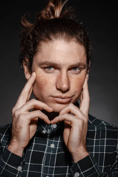 Portrait of a man with drawn hair and freckles, dressed in a checkered shirt