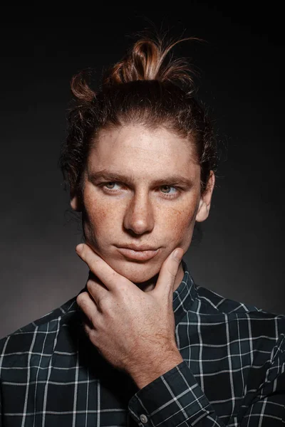 Portrait of a man with drawn hair and freckles, dressed in a checkered shirt