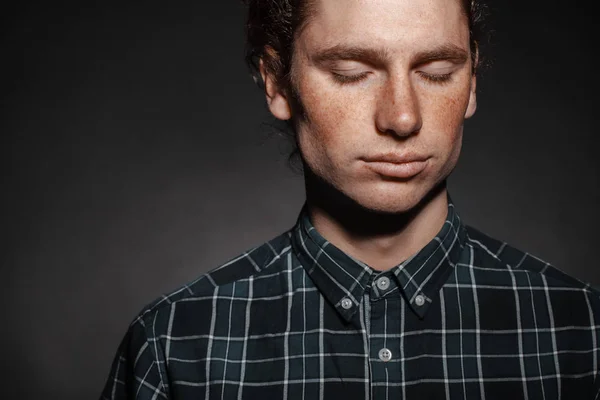Portrait of a man with drawn hair and freckles, dressed in a checkered shirt