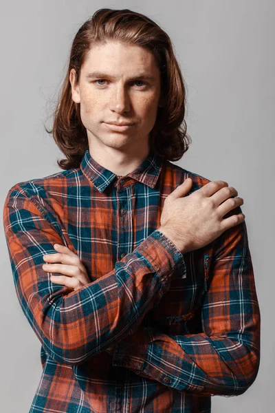 Portrét muže s dlouhými vlasy a pihy, oblečený v kostkované košili — Stock fotografie