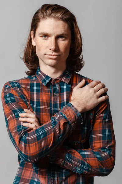 Retrato de un hombre de pelo largo y pecas, vestido con una camisa a cuadros —  Fotos de Stock