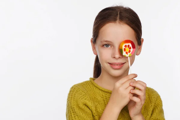 Emotionales Porträt eines achtjährigen Mädchens im gelb-grünen Pullover und mit einem Lutscher in der Hand — Stockfoto