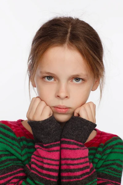 Portrait of 8-year-old girl in with her hair raised up and in a sweater in a crimson and green stripes Stock Photo