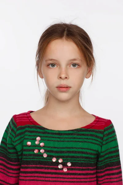 Porträt eines 8-jährigen Mädchens mit hochgezogenen Haaren und einem Pullover in einem purpurroten und grünen Streifen — Stockfoto