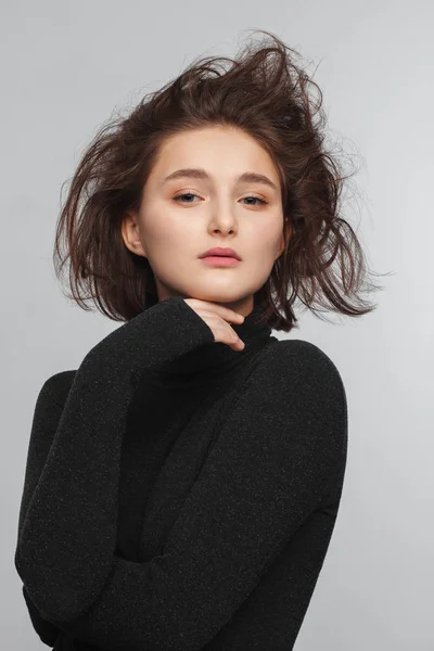 灰色の背景に黒いセーターの美しい十代の少女の肖像。髪を櫛で — ストック写真