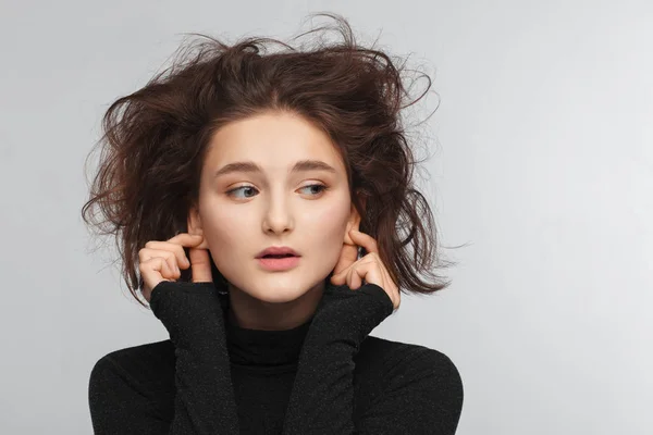 Retrato de una hermosa adolescente en un suéter negro sobre un fondo gris. Cabello peinado —  Fotos de Stock
