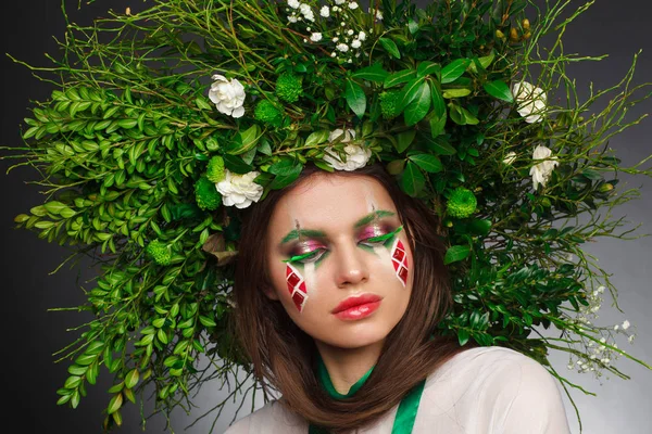 Portrait of a beautiful woman in a white dress with a green ribbon and with branches on her head. Creative makeup — Stock Photo, Image