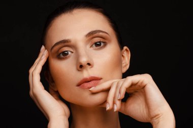 Siyah bir arka plan üzerinde toplanan saç ve çıplak omuzları ile güzel bir kadının portresi