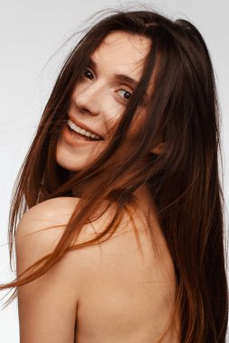 Rüzgardan ve çıplak omuzlardan uçan saçları olan genç ve güzel bir kadının portresi