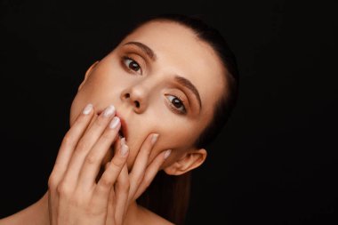 Siyah bir arka plan üzerinde toplanan saç ve çıplak omuzları ile güzel bir kadının portresi