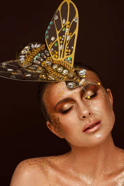 Portrait of a beautiful woman with expressive creative make-up in bronze and with a decoration on her head — Stock Photo, Image