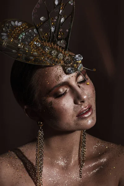 Portrait of a beautiful woman with expressive creative make-up in bronze and with a decoration on her head — Stock Photo, Image