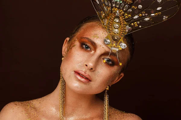 Portrait of a beautiful woman with expressive creative make-up in bronze and with a decoration on her head — Stock Photo, Image