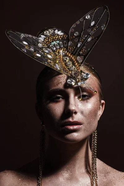 Portrait of a beautiful woman with expressive creative make-up in bronze and with a decoration on her head — Stock Photo, Image