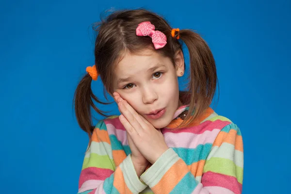 Porträt eines emotionalen Mädchens von fünf Jahren in einem gestreiften Pullover auf blauem Hintergrund — Stockfoto