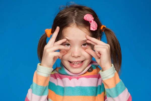 Retrato de uma menina emocional de cinco anos em uma camisola listrada em um fundo azul — Fotografia de Stock
