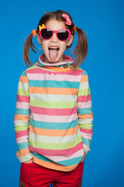 Porträt eines emotionalen Mädchens von fünf Jahren im gestreiften Pullover und mit Kinderbrille auf blauem Hintergrund — Stockfoto