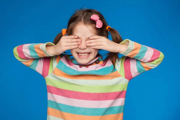 Porträt eines emotionalen Mädchens von fünf Jahren in einem gestreiften Pullover auf blauem Hintergrund — Stockfoto