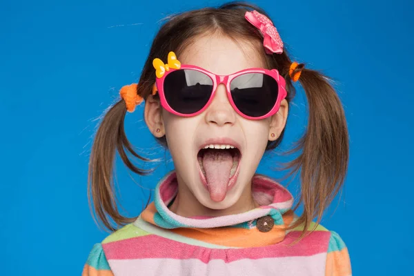 Retrato de uma menina emocional de cinco anos de idade em uma camisola listrada e em óculos infantis em um fundo azul — Fotografia de Stock