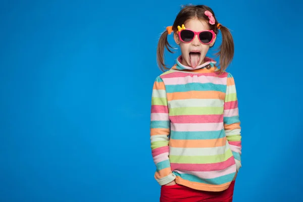 Retrato de uma menina emocional de cinco anos de idade em uma camisola listrada e em óculos infantis em um fundo azul — Fotografia de Stock