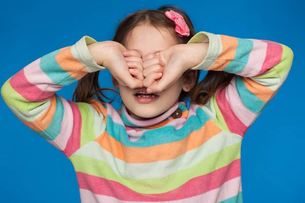 Retrato de uma menina emocional de cinco anos em uma camisola listrada em um fundo azul — Fotografia de Stock