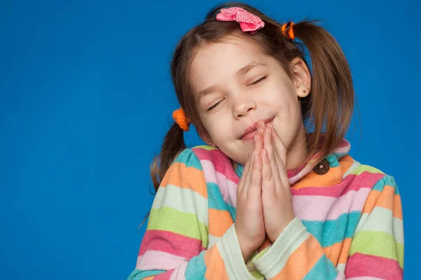 Porträt eines emotionalen Mädchens von fünf Jahren in einem gestreiften Pullover auf blauem Hintergrund — Stockfoto