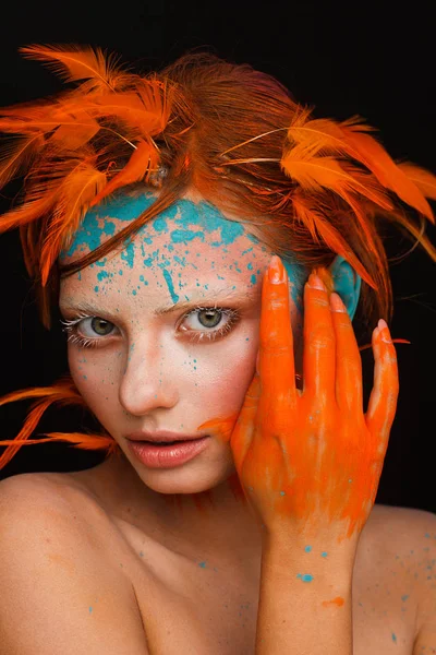Portrait of a beautiful model with creative make-up and hairstyle using orange feathers — Stock Photo, Image