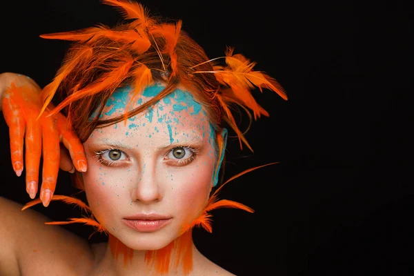 Portrait of a beautiful model with creative make-up and hairstyle using orange feathers — Stock Photo, Image