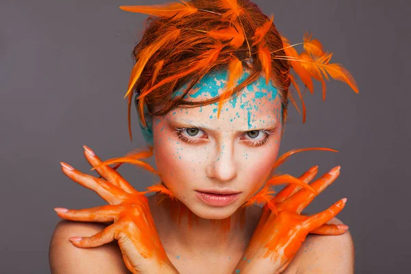 Portret pięknego modelu z kreatywnym makijażu i fryzurą za pomocą pomarańczowych piór — Zdjęcie stockowe