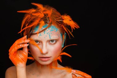 Turuncu tüyleri kullanarak yaratıcı makyaj ve saç modeli ile güzel bir model portresi