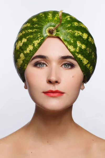 Retrato criativo de uma mulher com uma melancia na cabeça em vez de um chapéu. Fundo branco — Fotografia de Stock