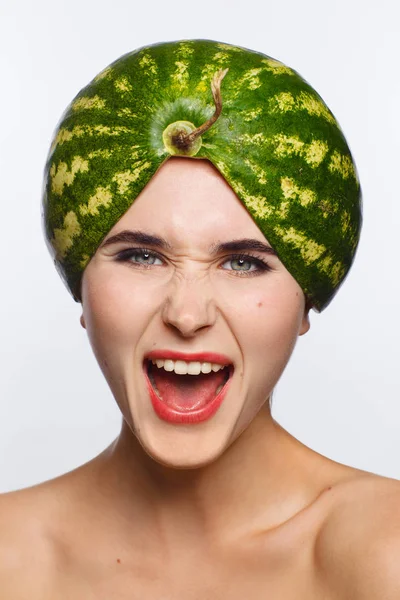 Creative portrait of a woman with a watermelon on her head instead of a hat. White background — Stock Photo, Image