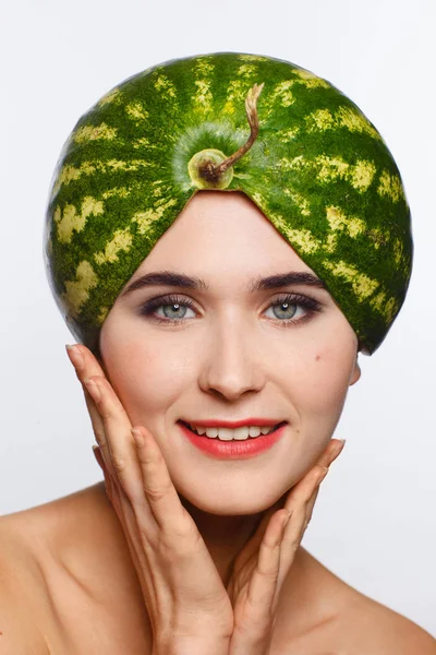 Creative portrait of a woman with a watermelon on her head instead of a hat. White background — Stock Photo, Image
