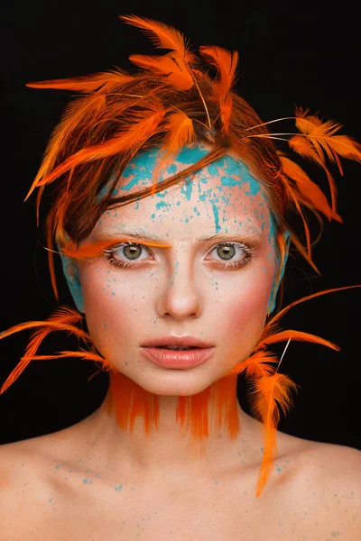 Portrait of a beautiful model with creative make-up and hairstyle using orange feathers — Stock Photo, Image
