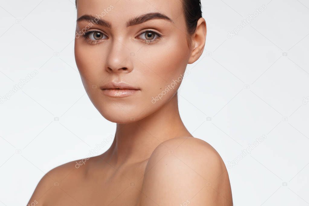 Portrait of a beautiful woman with collected hair and bare shoulders. Studio photo