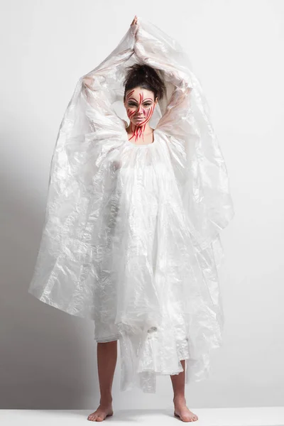 Model in a raincoat made of cellophane and in creative make-up