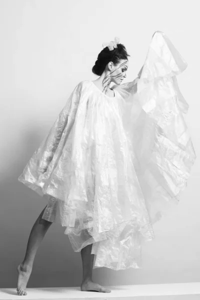 Model in a raincoat made of cellophane and in creative make-up