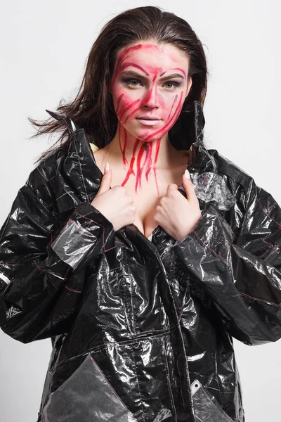 Model in a black raincoat made of cellophane and in creative make-up