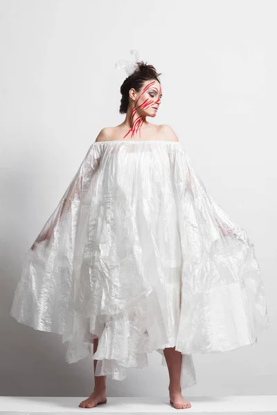 Model in a raincoat made of cellophane and in creative make-up
