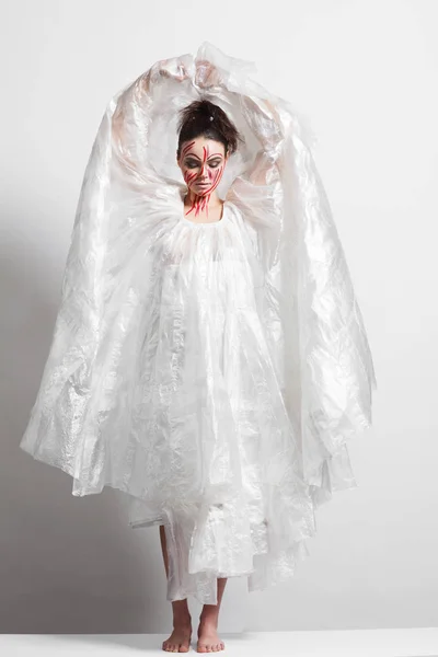 Modelo em uma capa de chuva feita de celofane e em maquiagem criativa — Fotografia de Stock