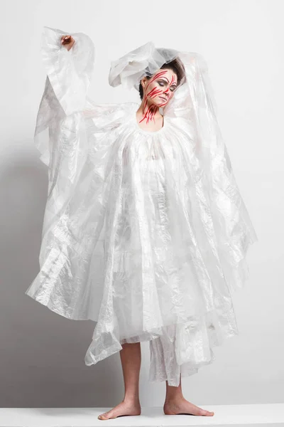 Model in a raincoat made of cellophane and in creative make-up