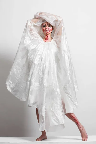 Model in a raincoat made of cellophane and in creative make-up