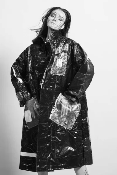 Modelo en un impermeable negro hecho de celofán y en maquillaje creativo Fotos de stock libres de derechos