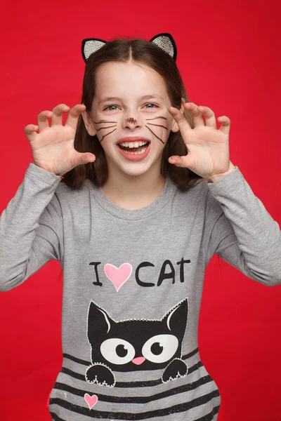 Kedi deseni ve kedi makyajı olan bir elbise içinde neşeli 8 yaşındaki bir kızın portresi