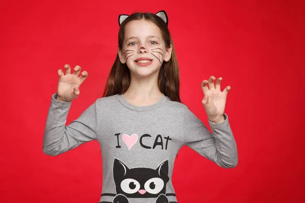 Kedi deseni ve kedi makyajı olan bir elbise içinde neşeli 8 yaşındaki bir kızın portresi
