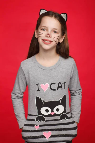 Retrato de uma menina alegre de 8 anos em um vestido com um padrão de gato e maquiagem de gato — Fotografia de Stock