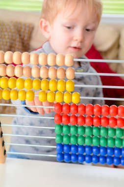 Çocuk saymayı öğreniyor. Genç çocuk matematik öğrenmek için bir abaküs kullanarak